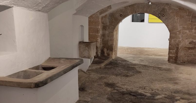 De oude wasruimte van het paleis Ses Carasses met stenen wasbakken, een bronzen stierbeeld en schilderijen, nu expositieruimte van Gerhardt Braun Gallery in Palma