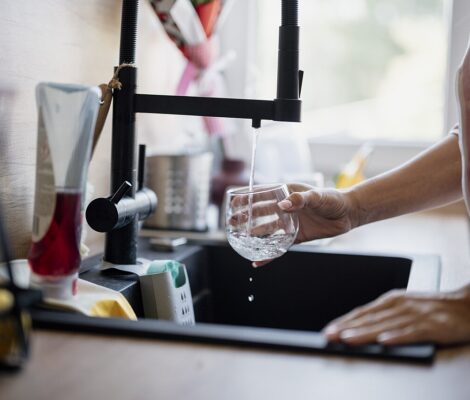 Een glas water wordt gevuld onder een keukenkraan