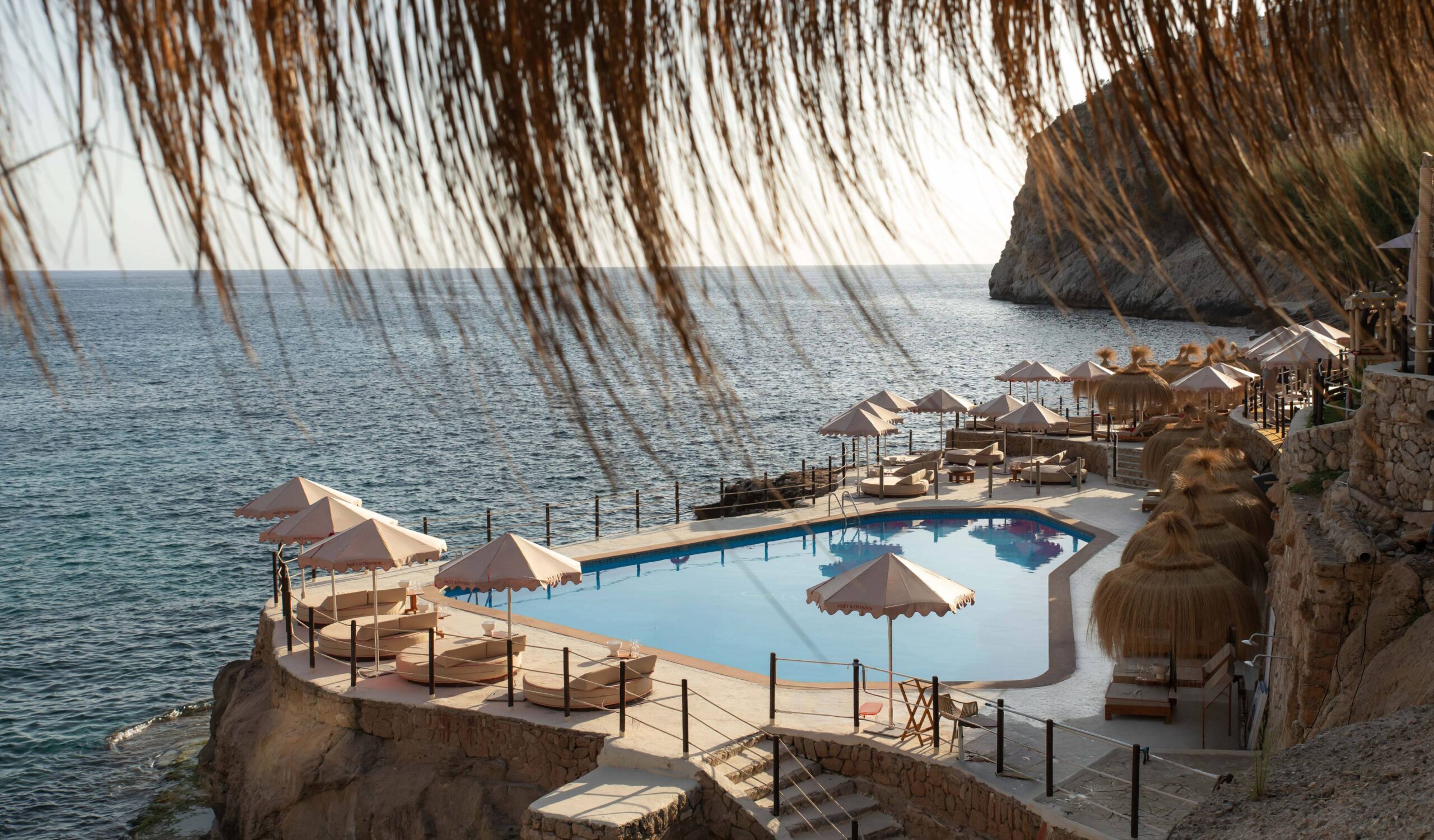 Gran Folies Mallorca: cliffside beachclub boven Cala Llamp bij Port d'Andratx 6 Het terras met parasols en ligbedden van Gran Folies boven Cala Llamp