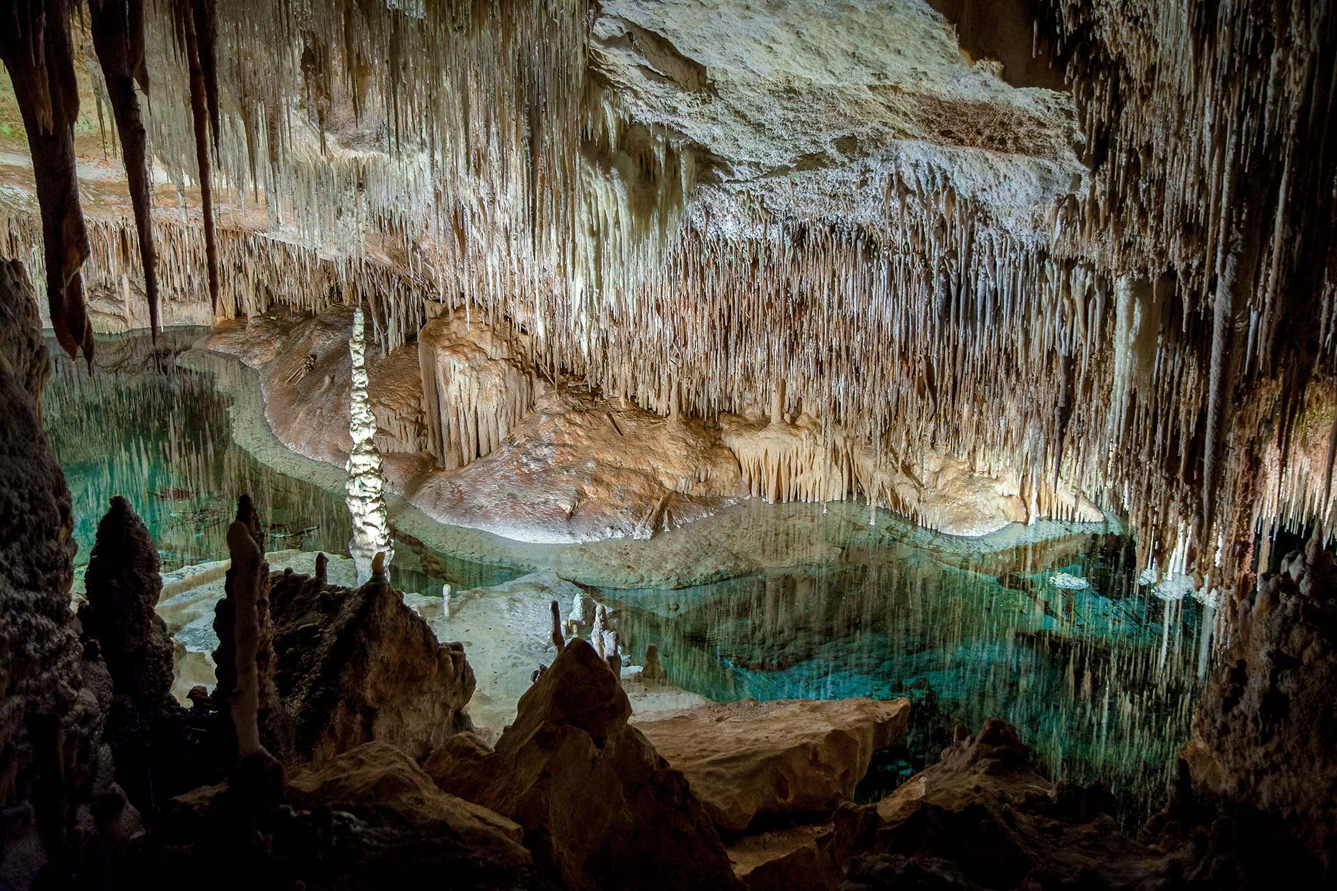 Helder ondergronds meer onder een plafond vol stalactieten in de Coves del Drach op Mallorca
