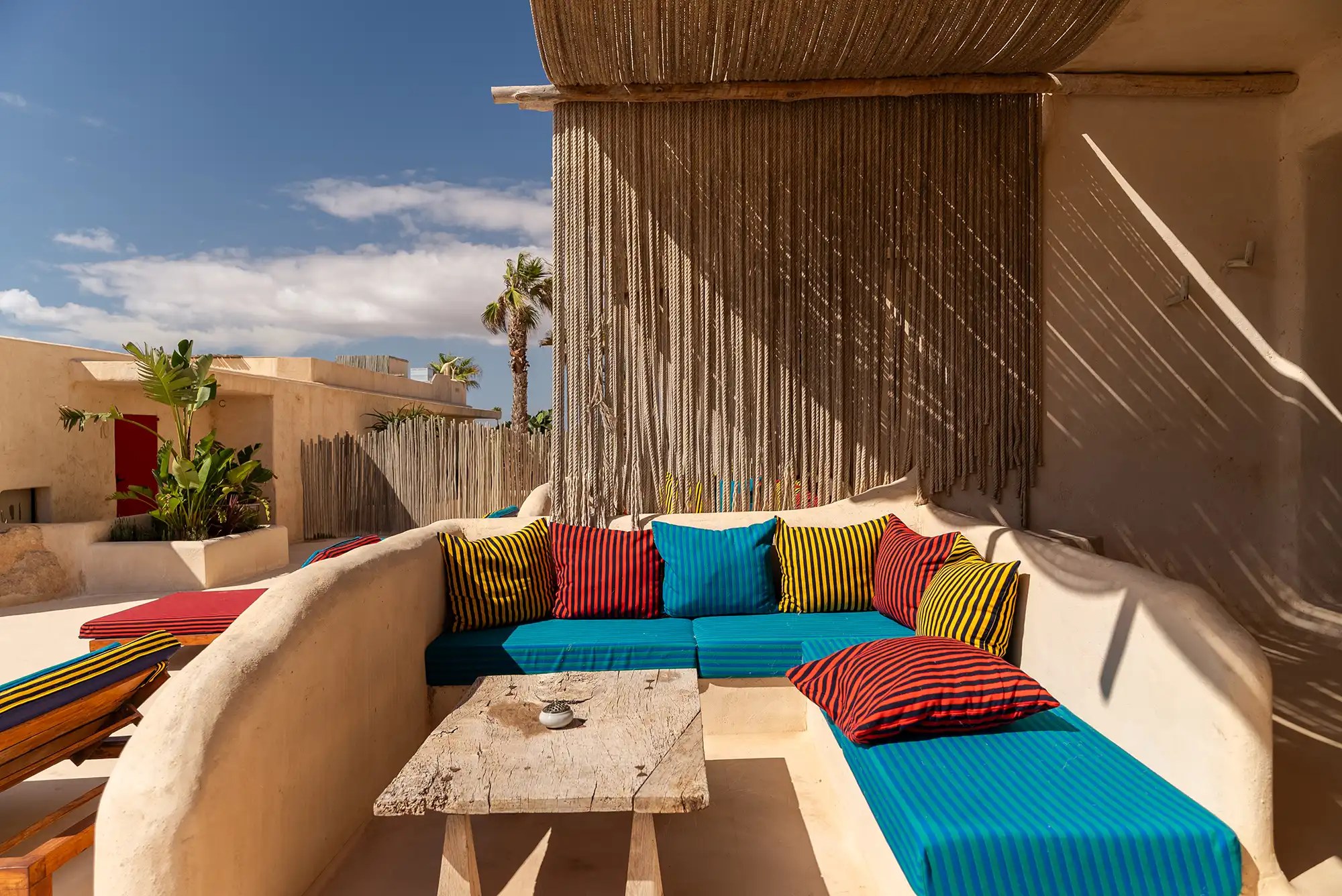 Hannah Formentera: strandrestaurant en sunset aan Es Arenals (Migjorn) 2 Loungehoek van Hannah Formentera met vrolijk gestreepte kussens onder een touwdak