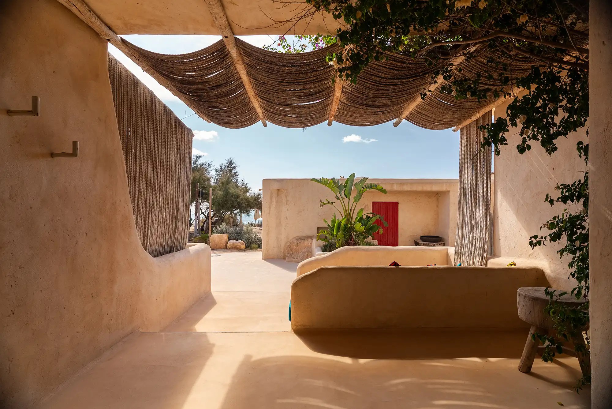 Hannah Formentera: strandrestaurant en sunset aan Es Arenals (Migjorn) 4 Overdekt terras van Hannah Formentera in lemen okertinten met een touwdak