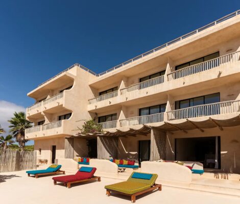 De strandgevel van Hannah Formentera met balkons en gekleurde ligbedden aan Playa de Es Arenals