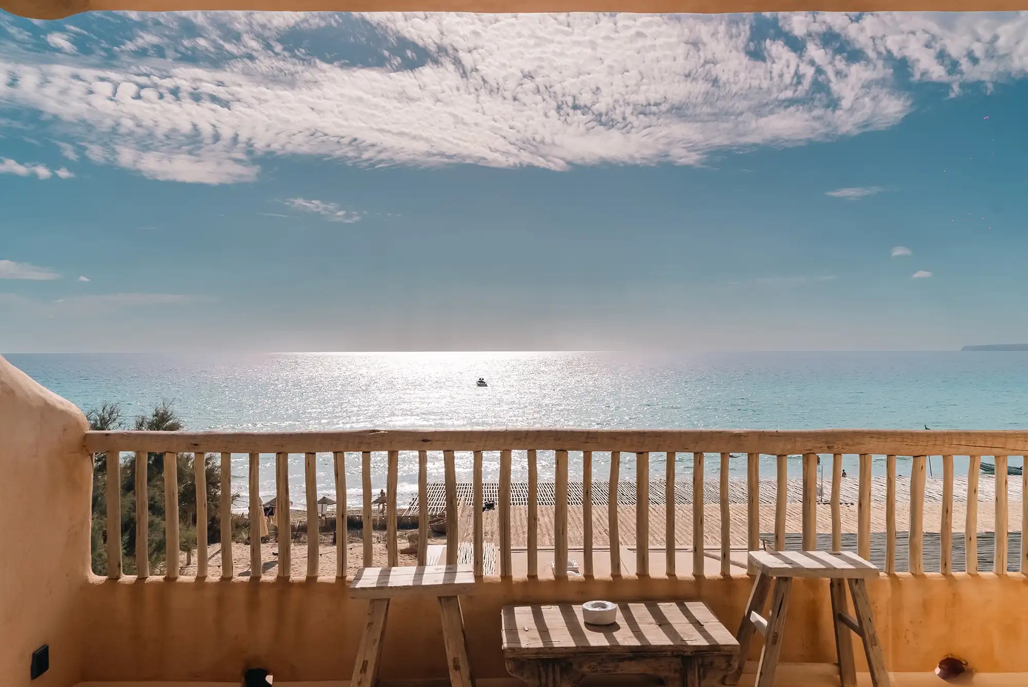 Hannah Formentera: strandrestaurant en sunset aan Es Arenals (Migjorn) 3 Terras van Hannah Formentera met een houten tafel en zeezicht over Playa de Es Arenals