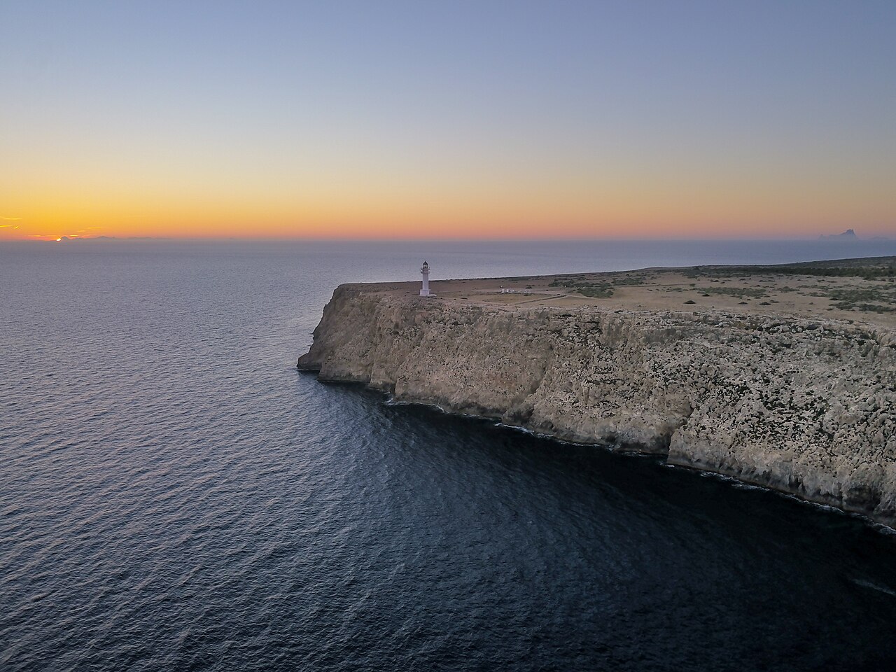 Hoe groot is Formentera? Oppervlakte, afmetingen en rijtijden 5 De kliffen van de Cap de Barbaria op Formentera bij zonsondergang, met de vuurtoren op de rand