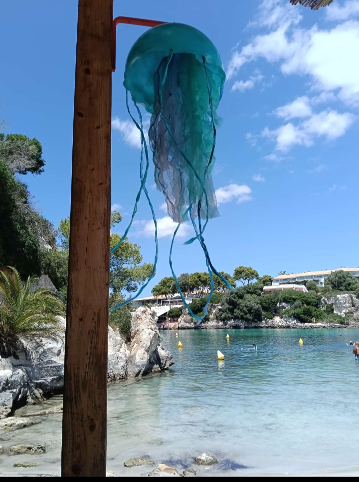 Zeegroene kwal-decoratie boven het strand van Cala en Blanes bij Hopi Beach Bar