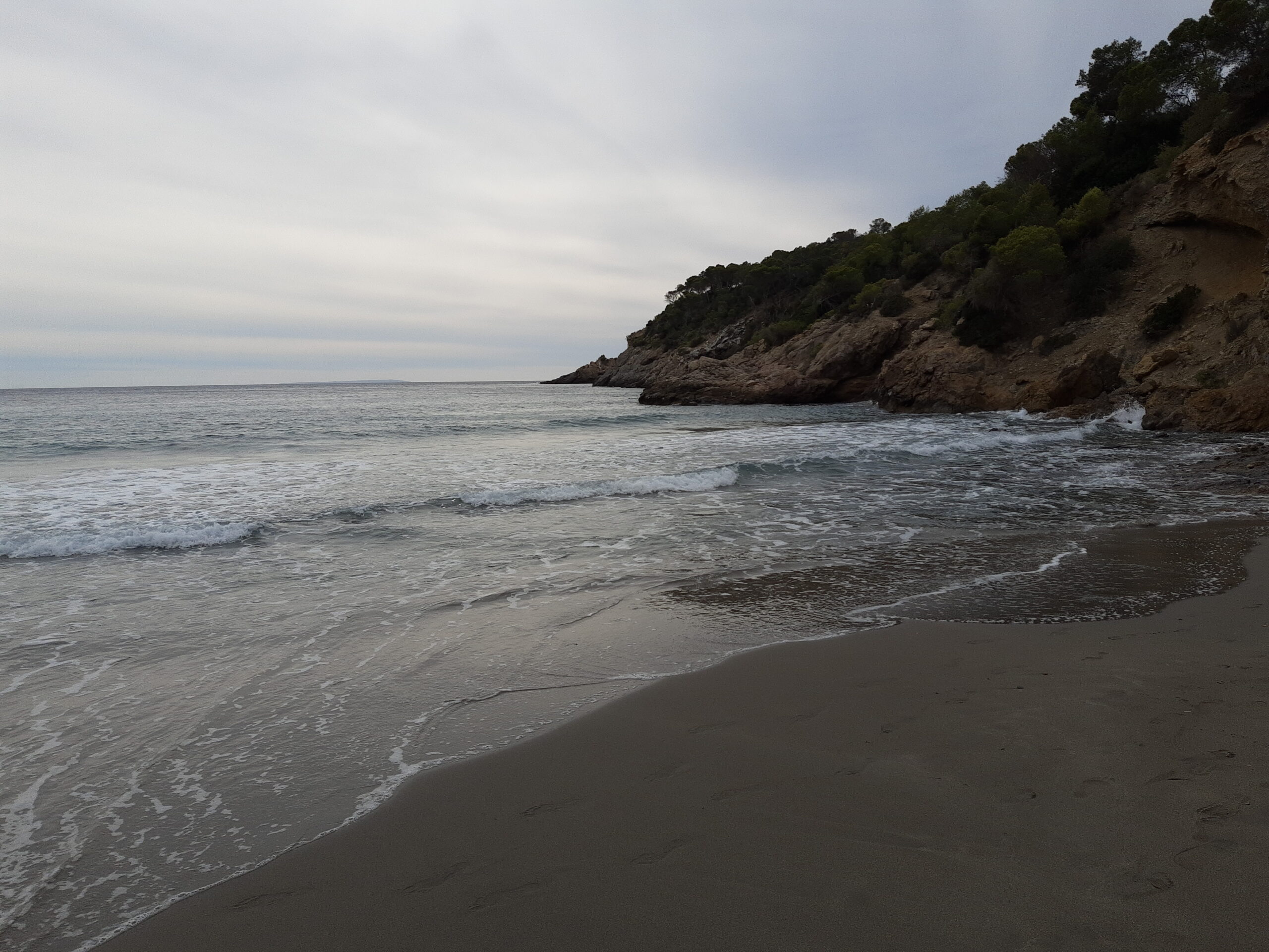 Het verlaten strand van Cala Boix op Ibiza onder een bewolkte lucht