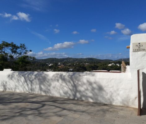 De witte kerkplaza van Santa Eulària des Riu op Ibiza, met uitzicht over het groene binnenland in november