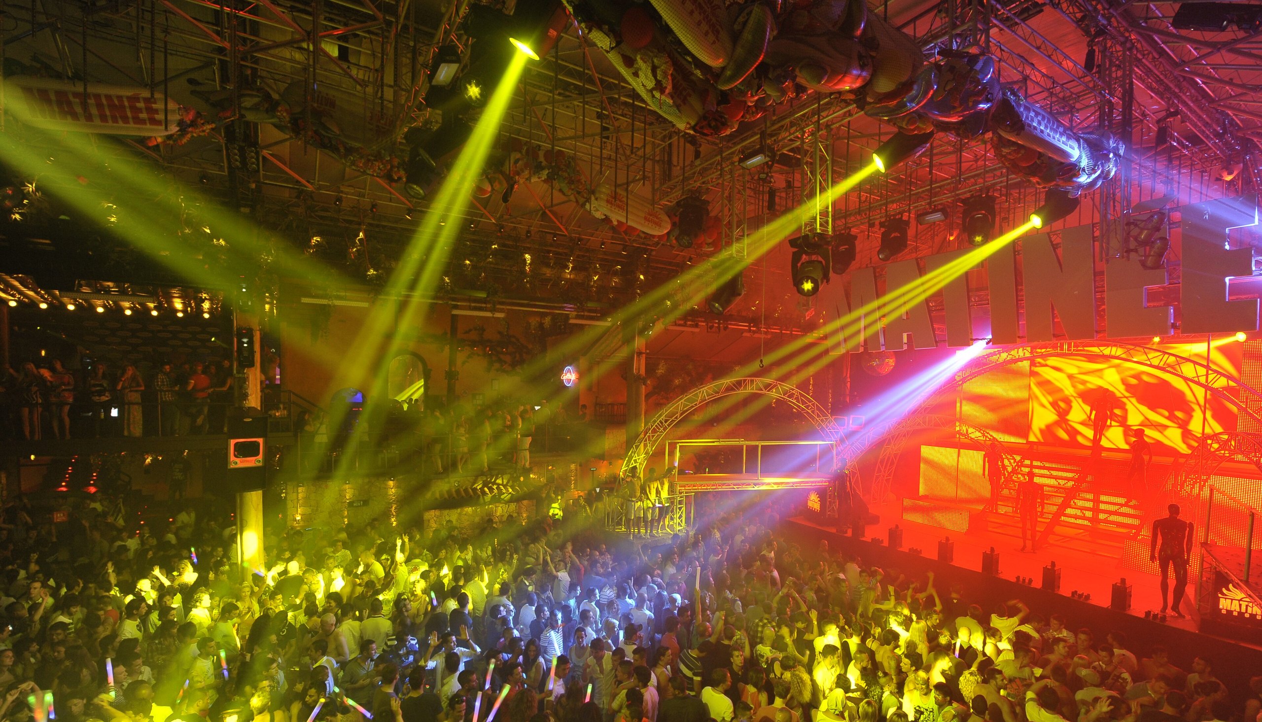 Gele en rode lichtbundels boven een volle dansvloer in club Amnesia op Ibiza