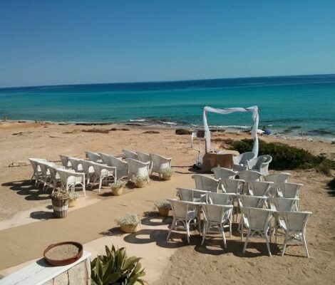 Gedekte tafels en witte stoelen op het zand aan een strand op Formentera