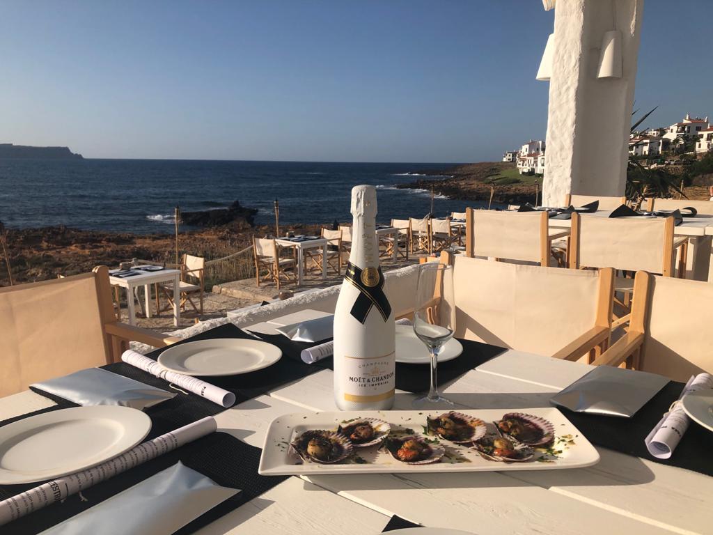 Gedekte tafel met champagne en een gerecht op het terras van Isabella Beach Club