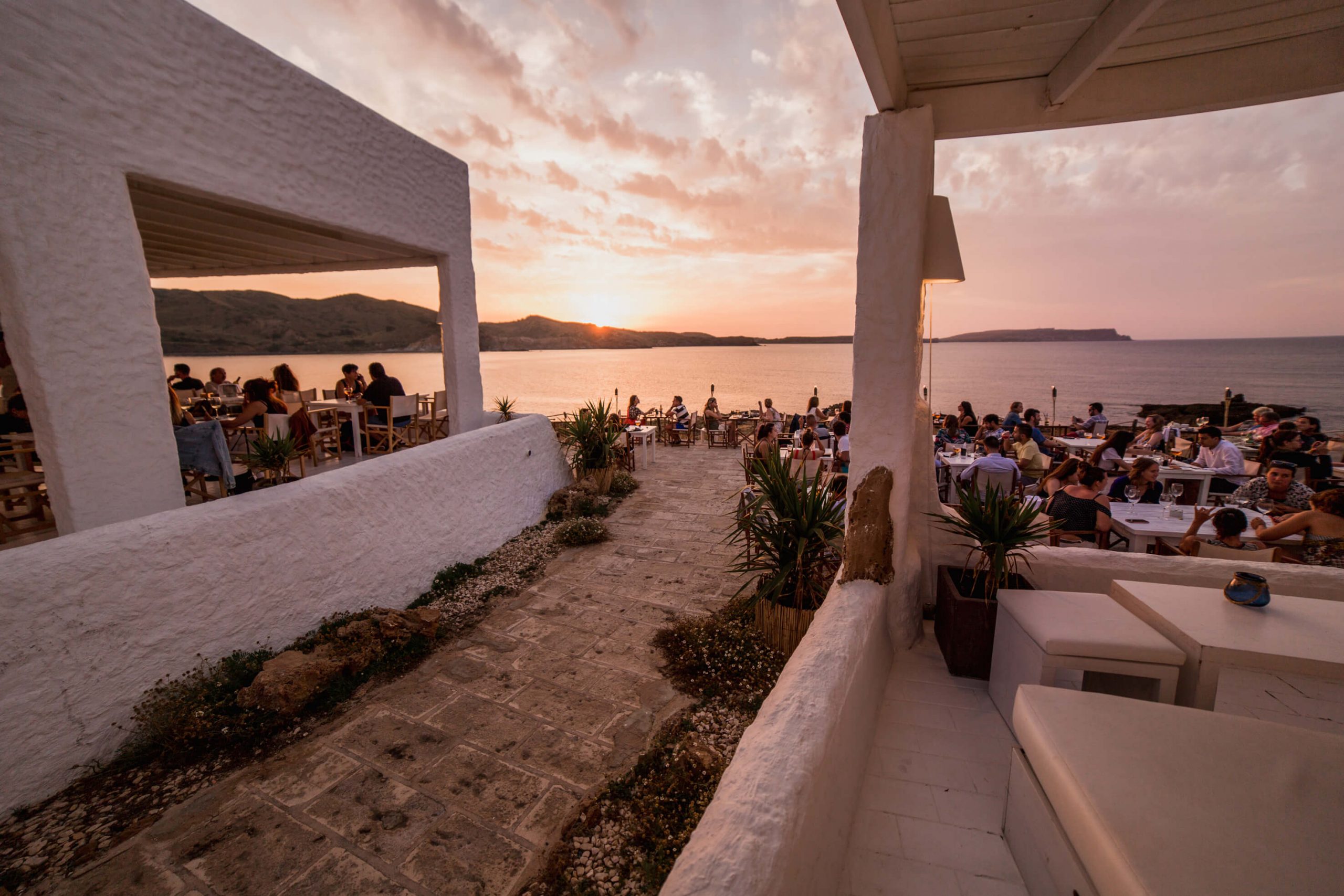 Het overdekte terras van Isabella Beach Club vol gasten in het gouden uur