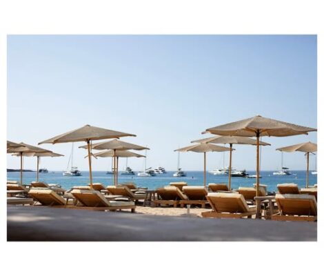 Het terras van Jondal aan Cala Jondal met parasols, ligbedden en de zee