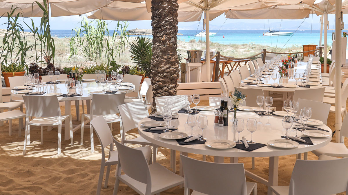 Juan y Andrea Formentera: het strandrestaurant voor de jachten op Ses Illetes 2 Het terras met ronde tafels en zonnedoeken van Juan y Andrea aan het strand van Ses Illetes