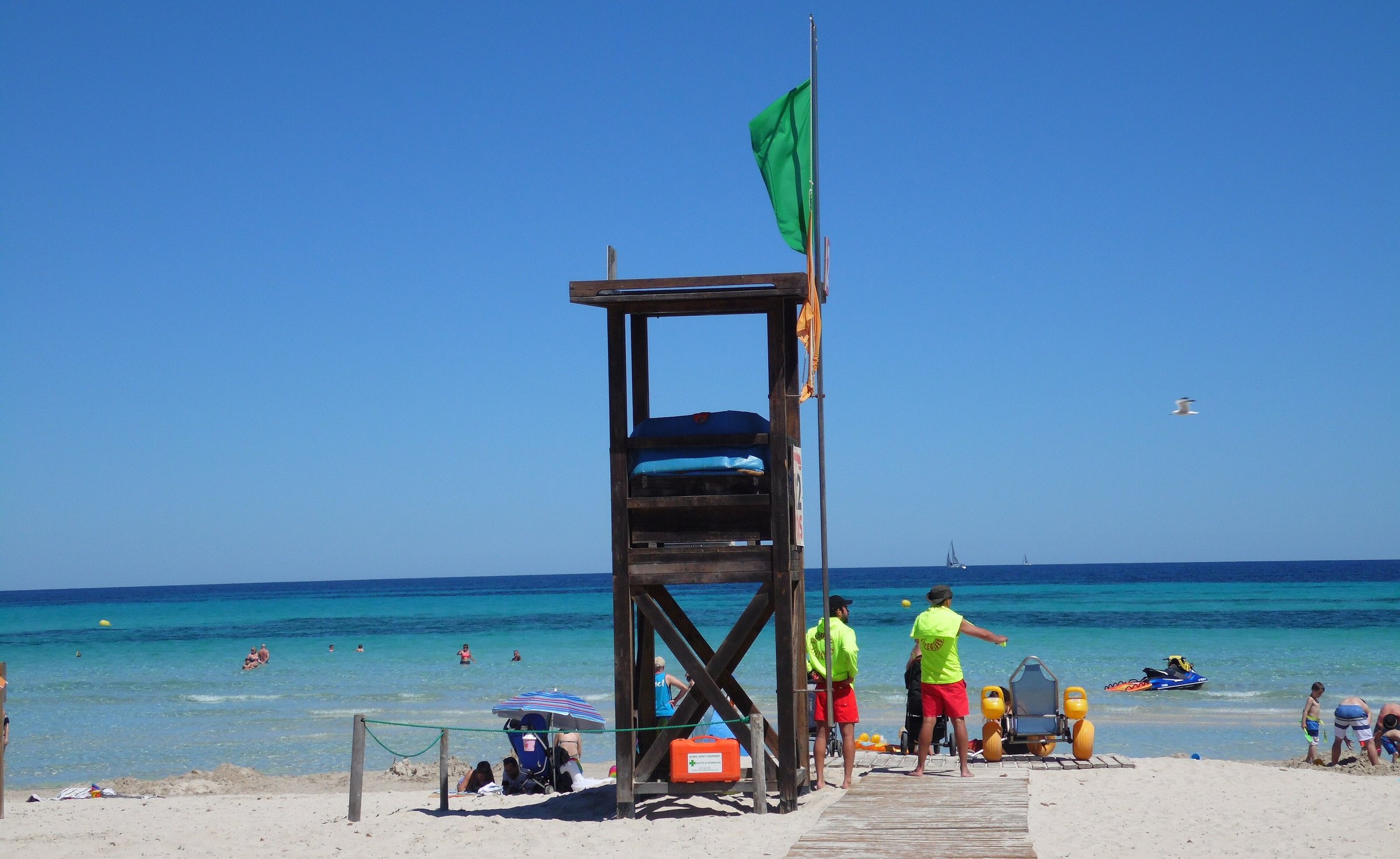 Houten strandwachtpost met groene vlag en strandwachten op het strand van Sa Coma op Mallorca