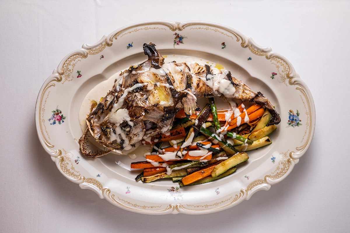 Een hoofdgerecht met vis en groenten op een sierschaal bij La Cocina de Cristine