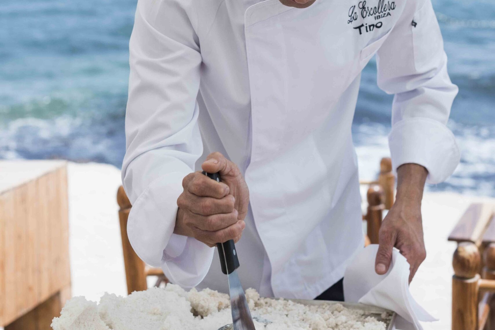 Kok van La Escollera op Ibiza die een in zout gebakken vis openbreekt