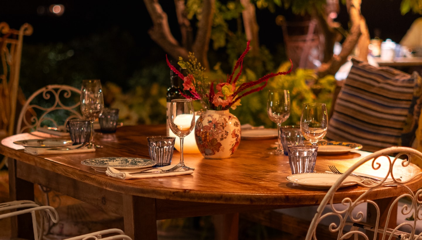 La Paloma Ibiza: tuinrestaurant tussen de citrusbomen van Sant Llorenç 4 Een houten tafel in de tuin van La Paloma, 's avonds gedekt met kaarslicht, bloemen en wijnglazen