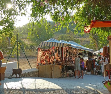 Kraampjes met tassen, sieraden en textiel onder de bomen van de hippiemarkt Las Dalias in Sant Carles, Ibiza