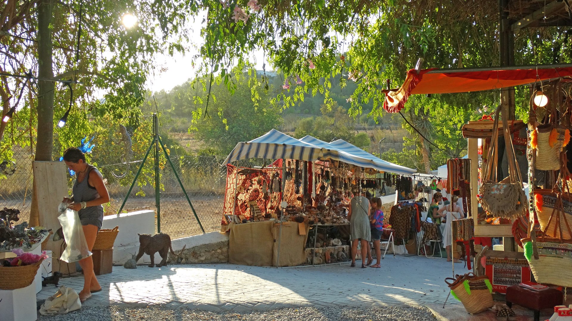 Bezienswaardigheden Ibiza: wat je echt gezien moet hebben 3 Kraampjes met tassen, sieraden en textiel onder de bomen van de hippiemarkt Las Dalias in Sant Carles, Ibiza