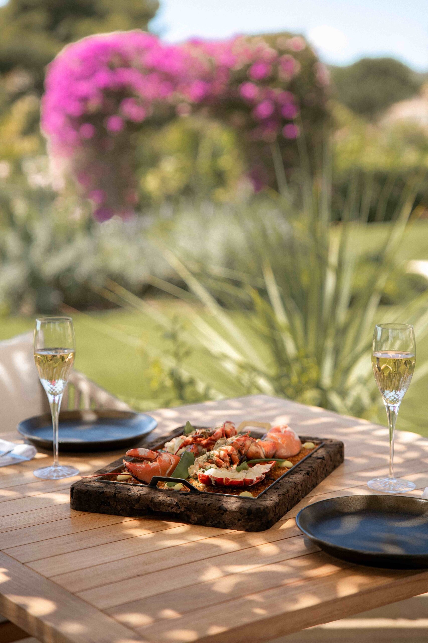 Bord met zeevruchten en twee glazen rosewijn op het terras van Mar Sea Club