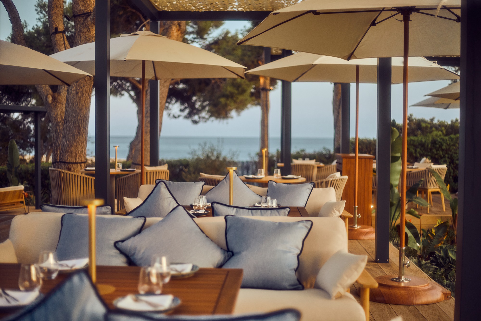 Loungebanken en parasols op het terras van Mar Sea Club met de zee op de achtergrond