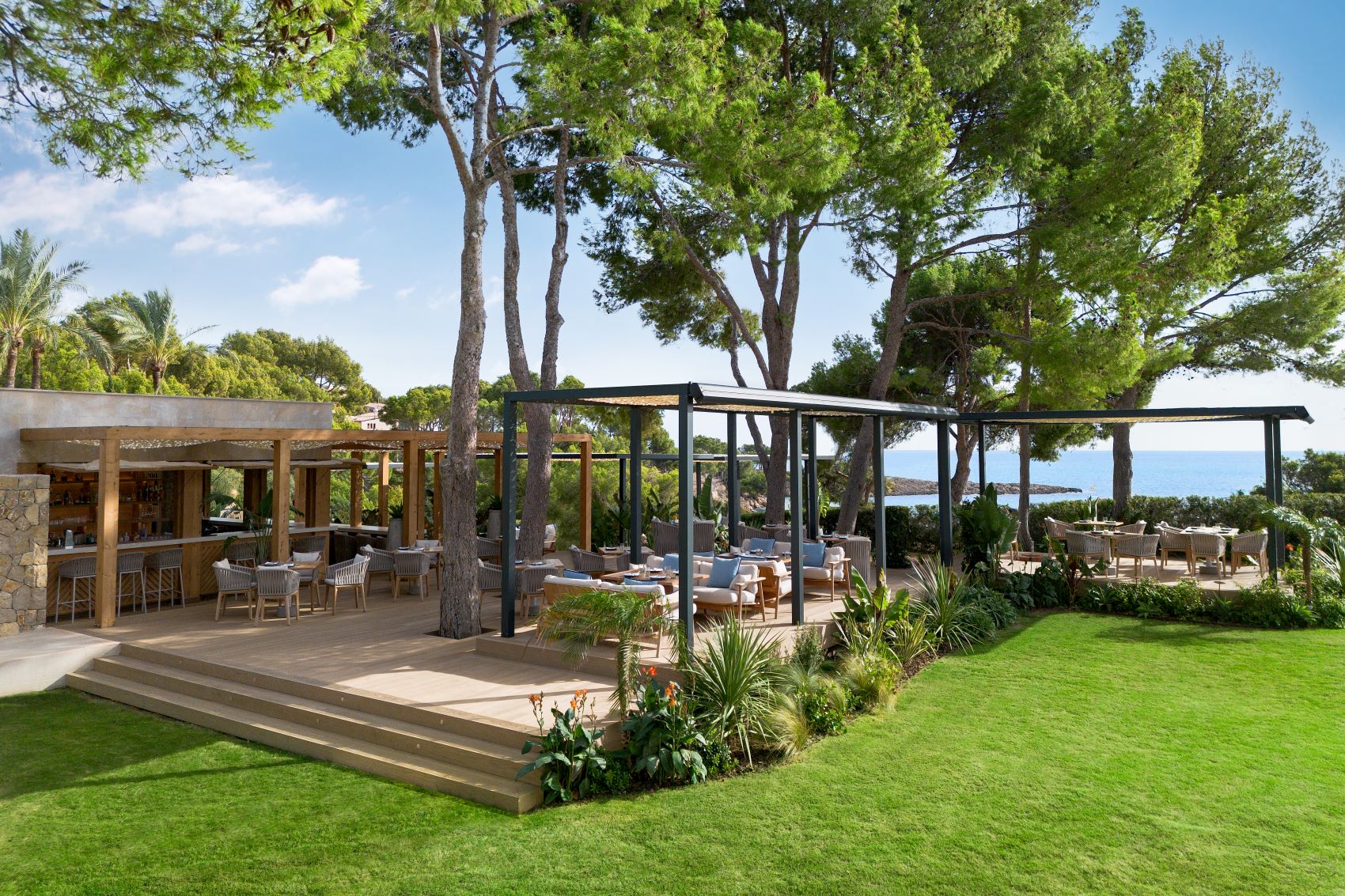 Het restaurant van Mar Sea Club met pergola, gazon en zee op de achtergrond