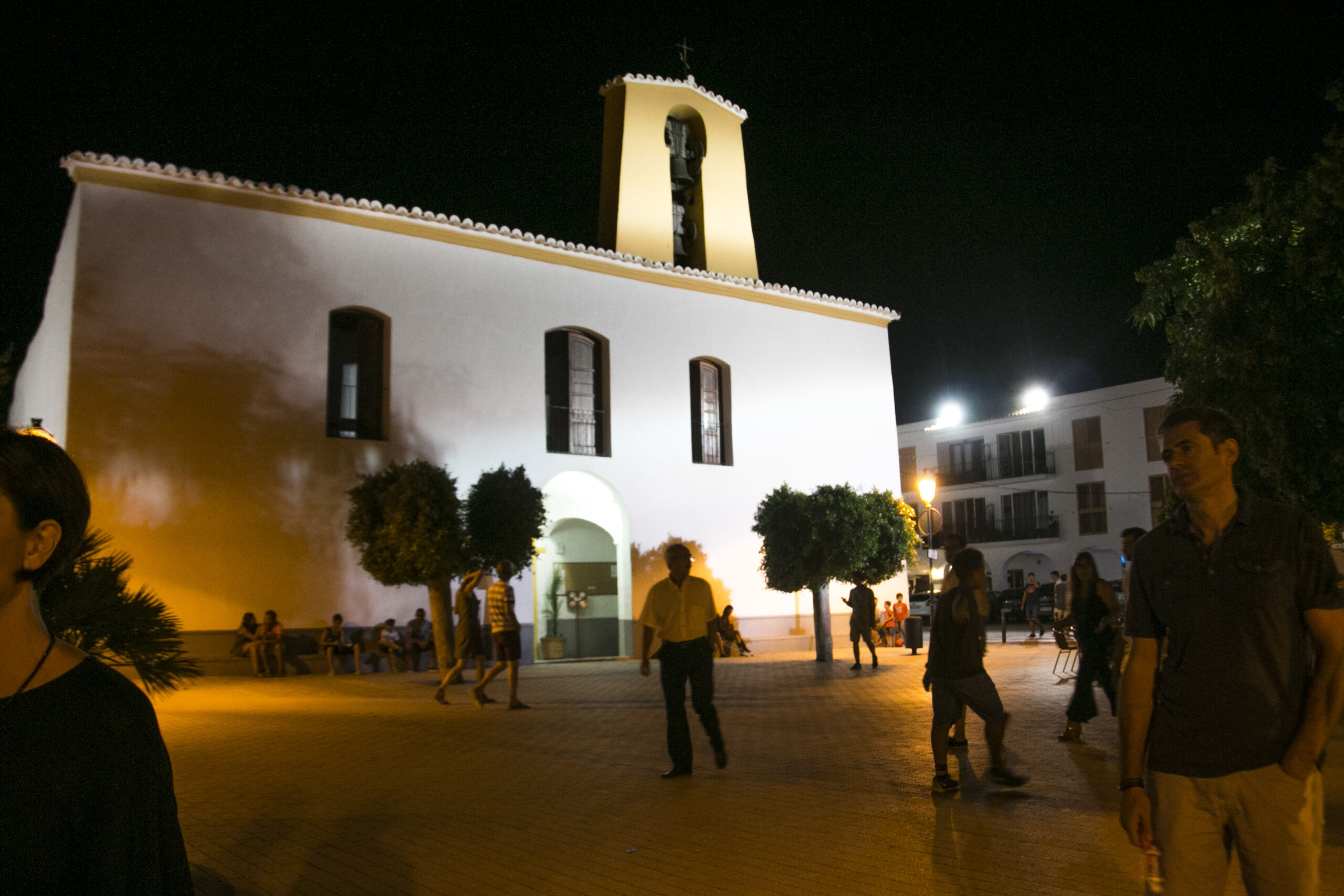 Het verlichte kerkplein van Santa Gertrudis op Ibiza in de zomeravond, waar op vrijdag de ambachtsmarkt staat