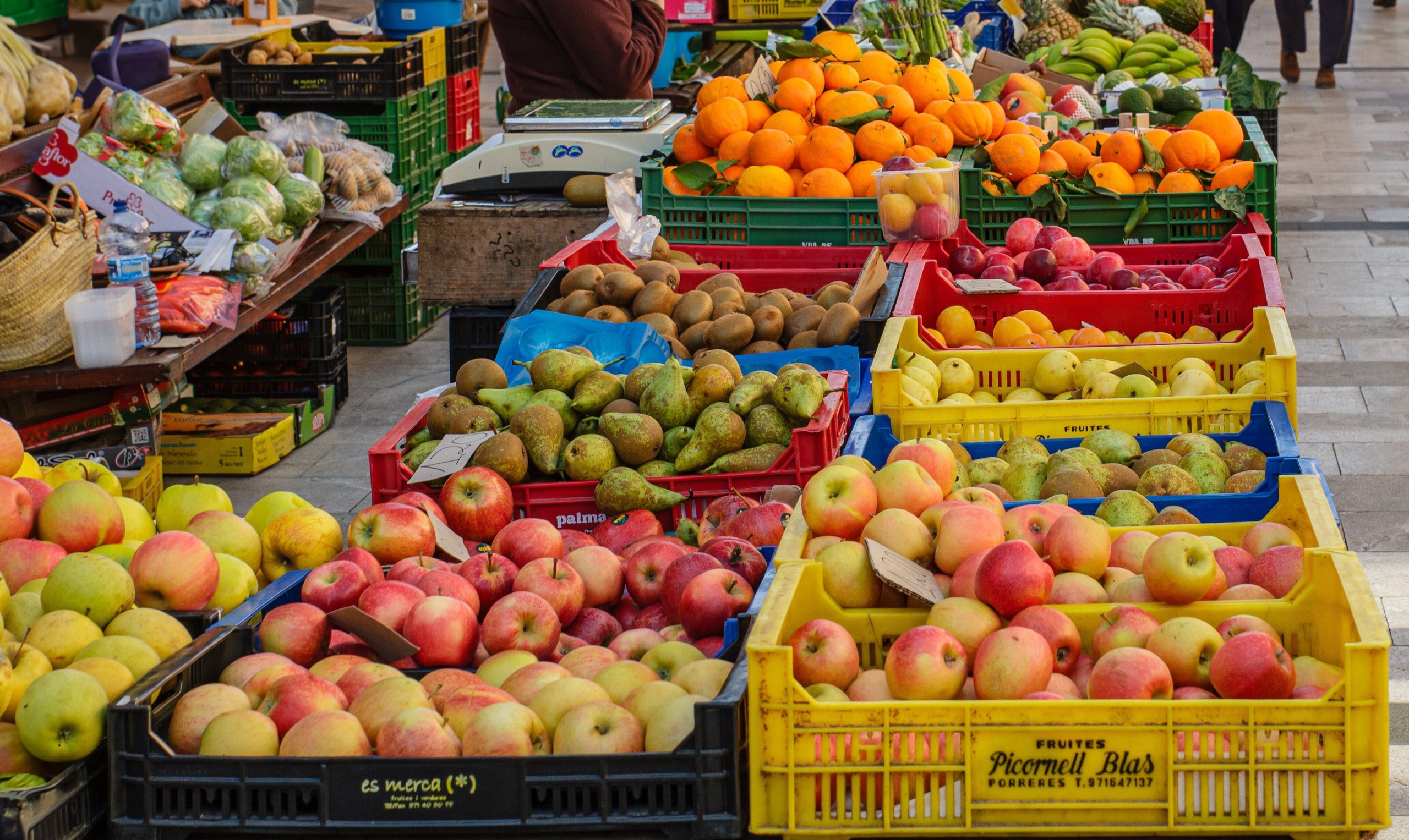 Fruitkraam op de weekmarkt van Santanyí op Mallorca met kratten appels, peren, kiwi's en sinaasappels