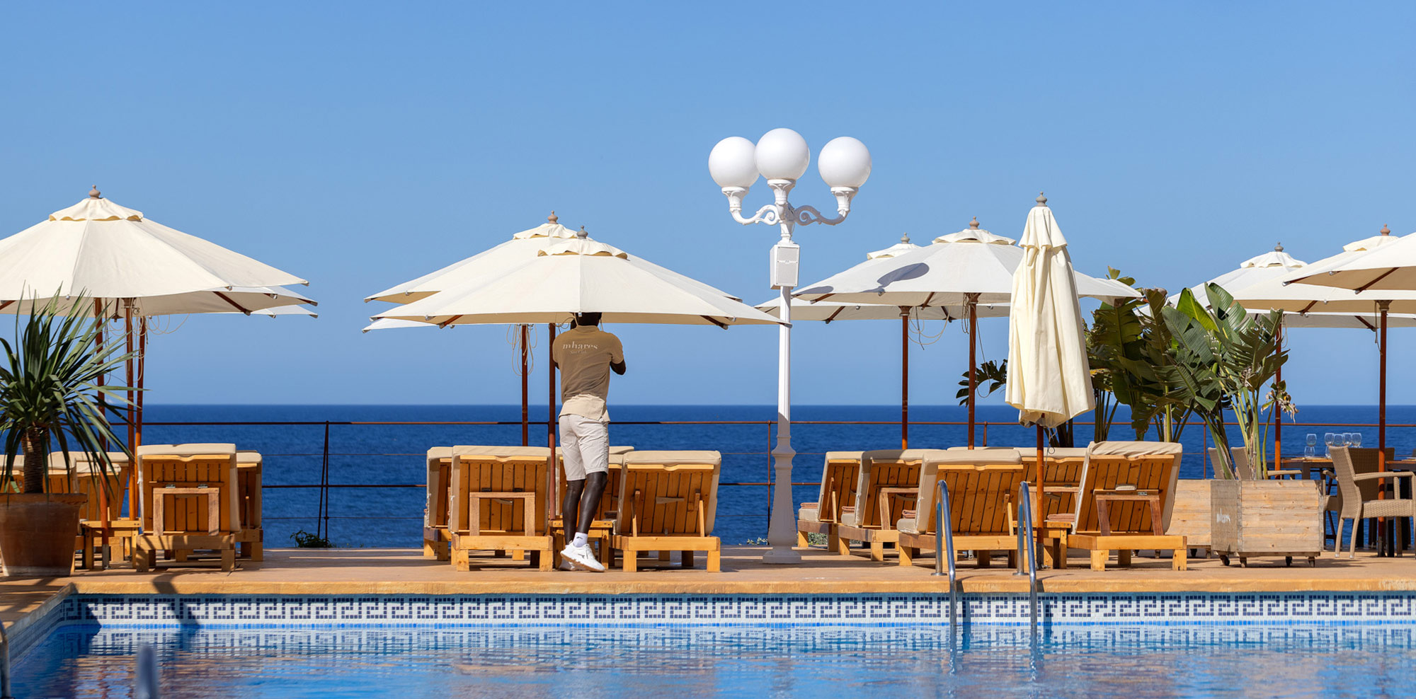 Het zwembad en de parasols van Mhares Sea Club met de Baai van Palma erachter
