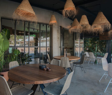 Het lichte interieur van Moos in Cala Llonga met rieten lampen, houten tafels en groen