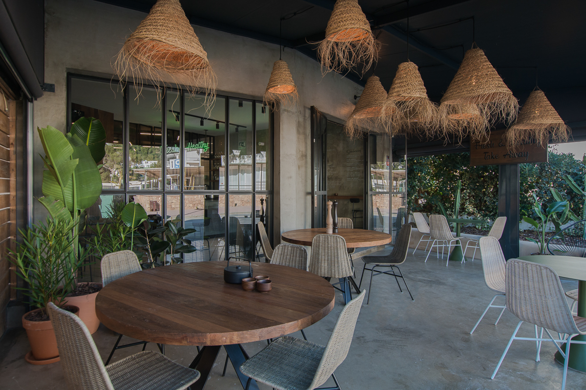 Het lichte interieur van Moos in Cala Llonga met rieten lampen, houten tafels en groen