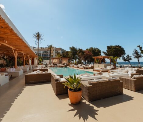 Het witte zwembad en de ligbedden van Nikki Beach Ibiza met de zee erachter