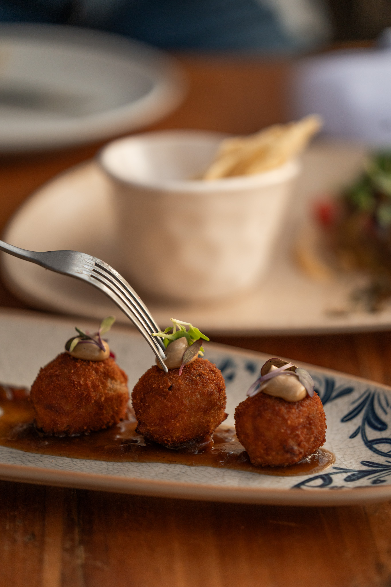 Ñora Beach Ibiza: strandrestaurant en ligbedden aan Port des Torrent 8 Croquetas van gestoofde kalfswang op een bord bij Ñora Beach