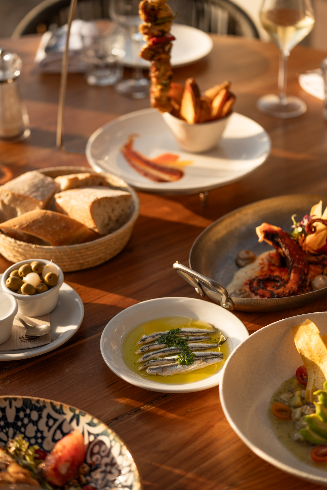 Ñora Beach Ibiza: strandrestaurant en ligbedden aan Port des Torrent 3 Gedekte tafel bij Ñora Beach met verschillende gerechten om te delen