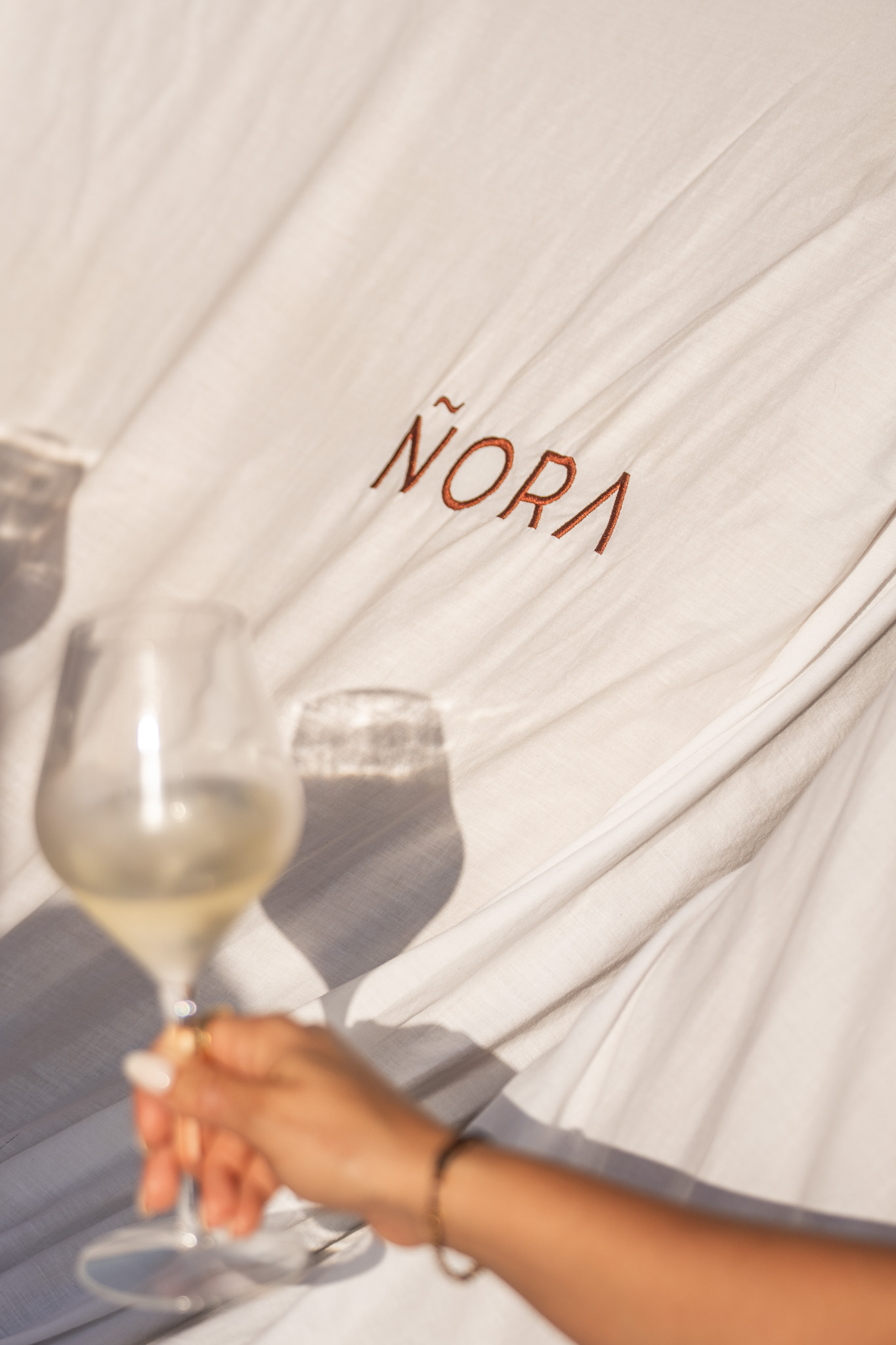 Ñora Beach Ibiza: strandrestaurant en ligbedden aan Port des Torrent 4 Ligbed met handdoek van Ñora Beach en twee glazen wijn op het strand