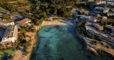 Ñora Beach Ibiza: strandrestaurant en ligbedden aan Port des Torrent 22 De baai van Port des Torrent op Ibiza vanuit de lucht, met Ñora Beach aan het zand