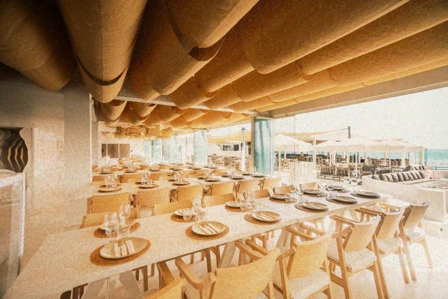 NU Mallorca: beachclub en restaurant op Playa de Muro (baai van Alcúdia) 2 De witte eetzaal van NU Mallorca met gedekte tafels en een houten plafond