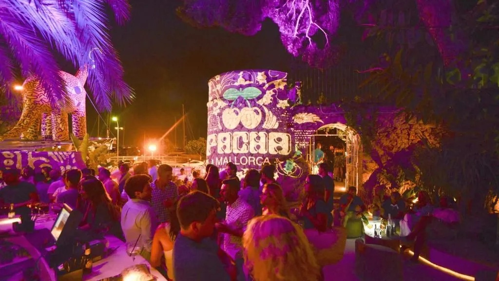 Het verlichte terras van Pacha Mallorca aan de Paseo Marítimo in Palma op een zomeravond, met de karakteristieke ronde toren met het kersenlogo