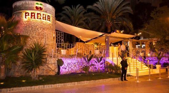 De ronde stenen toren van Pacha Mallorca met het verlichte kersenlogo boven de naam