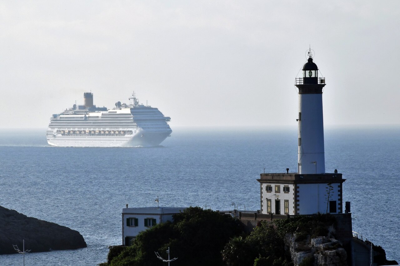 Een cruiseschip vaart langs de vuurtoren de haven van Ibiza binnen