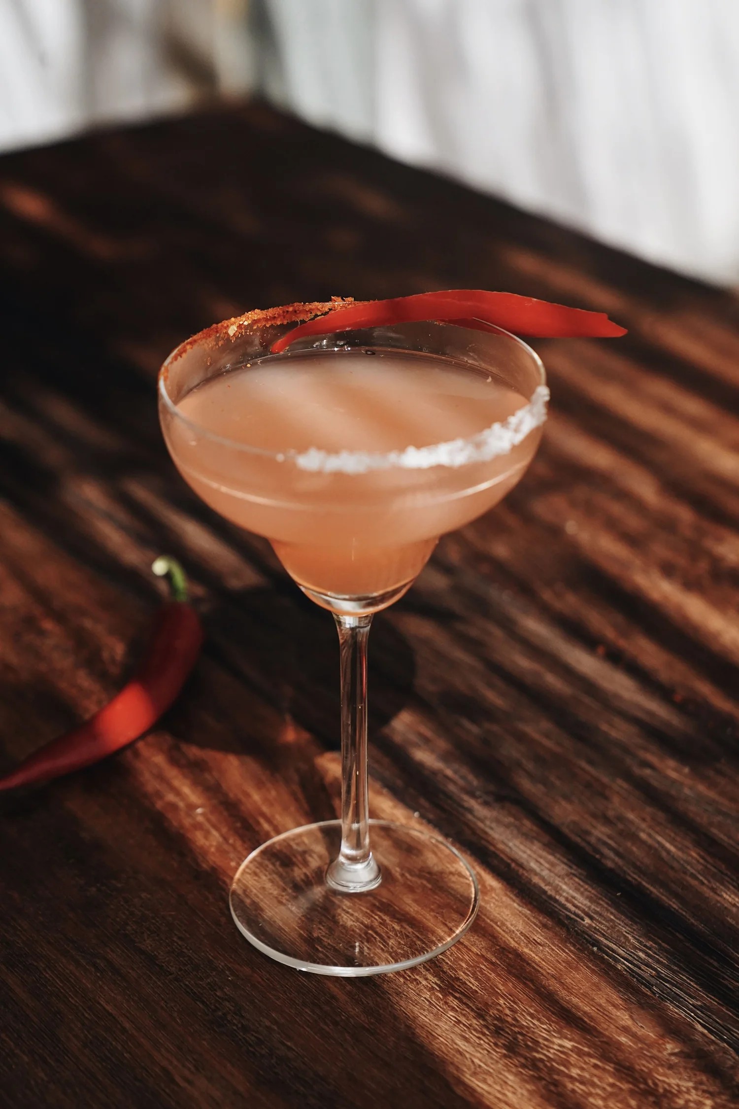 Cocktail met chili op een houten tafel bij Patiki Beach