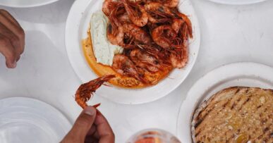 Gedekte tafel met gegrilde gamba's, brood en drankjes om te delen bij Patiki Beach