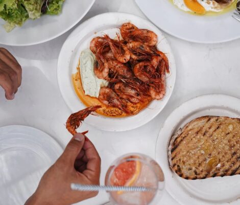 Gedekte tafel met gegrilde gamba's, brood en drankjes om te delen bij Patiki Beach