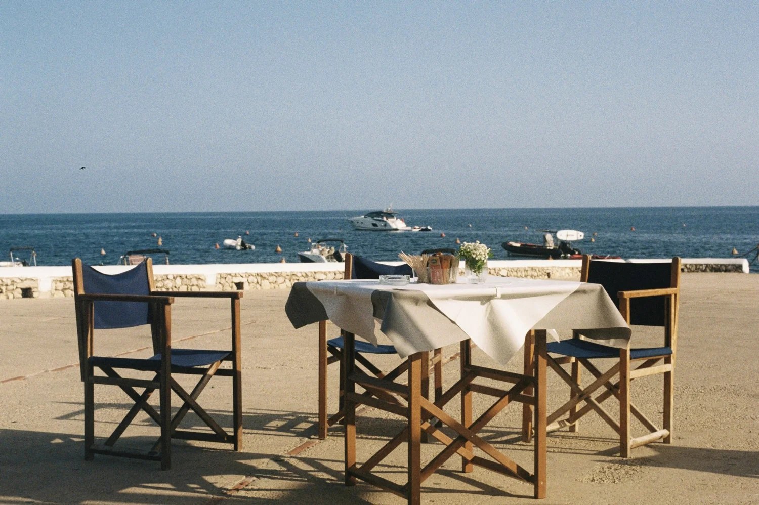 Gedekte tafel met wit tafelkleed op het terras van Paupa vlak aan de zee