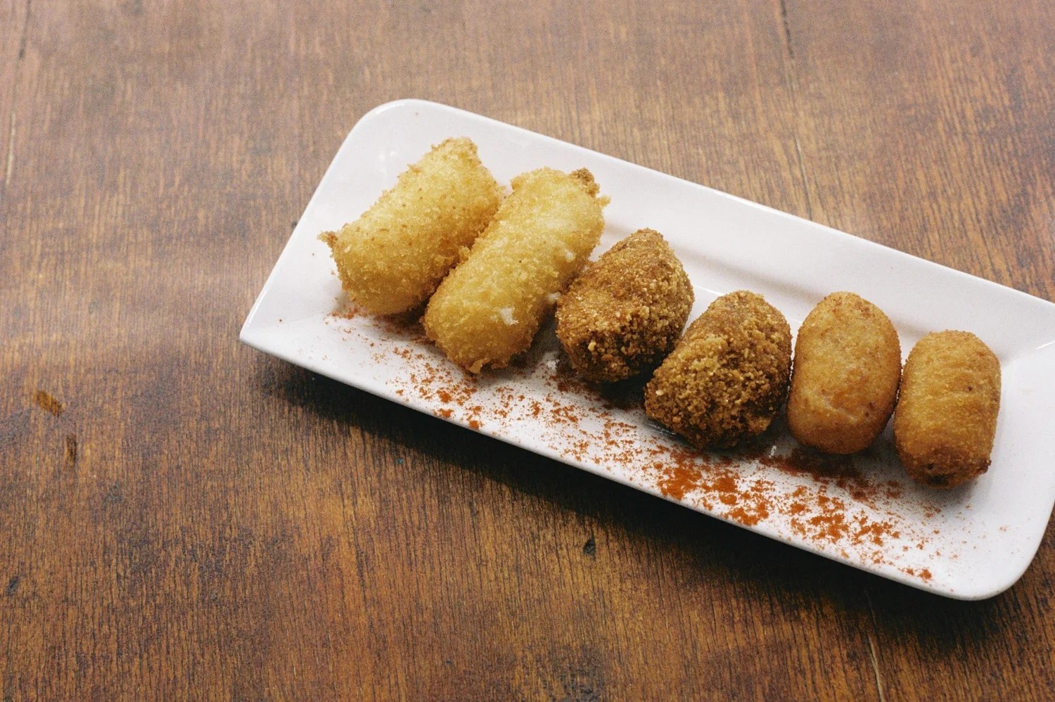 Bord met knapperige kroketten op een houten tafel bij Paupa op Menorca