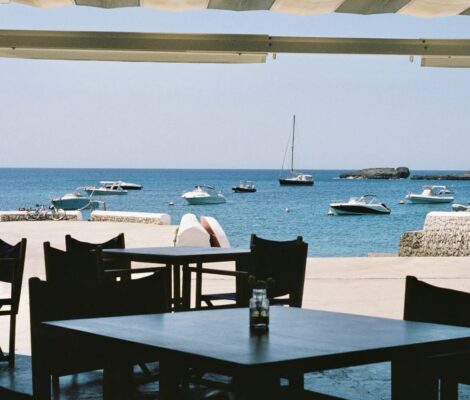 Het terras van Paupa onder het zonnescherm met uitzicht op de baai en de bootjes van Cala Torret op Menorca