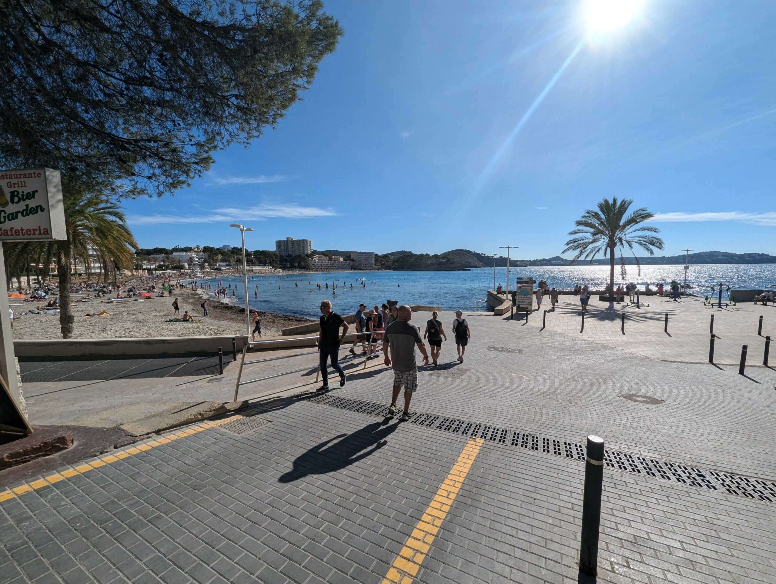De vernieuwde boulevard van Peguera langs het strand Palmira, met wandelaars, palmen en de baai op de achtergrond