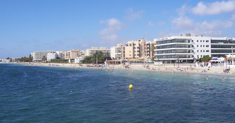 Het lange zandstrand van Playa d'en Bossa op Ibiza met hotels langs de kust en helder blauw water