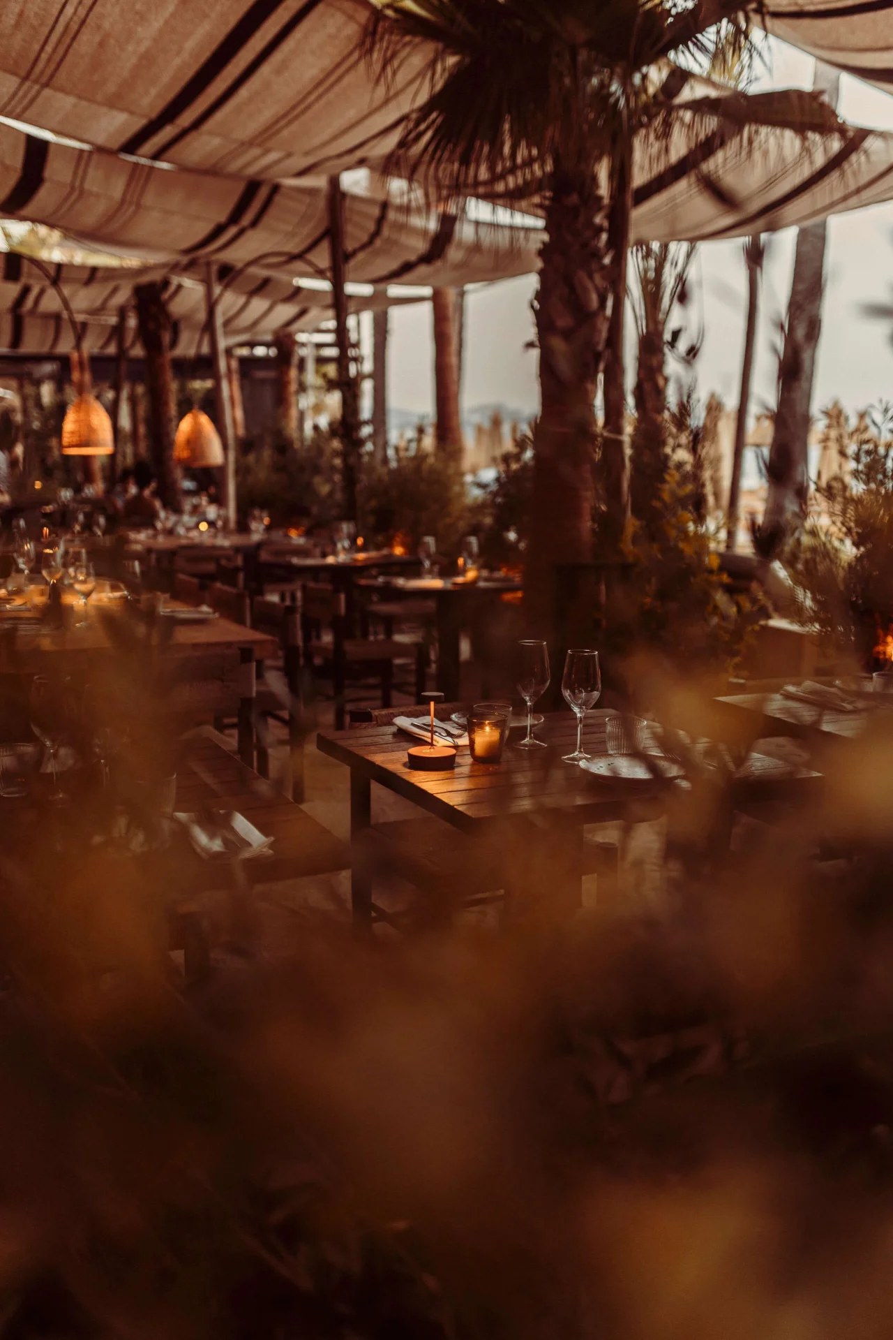 Het overdekte terras van Playa Soleil op Ibiza in de schemering, met hangende lampen